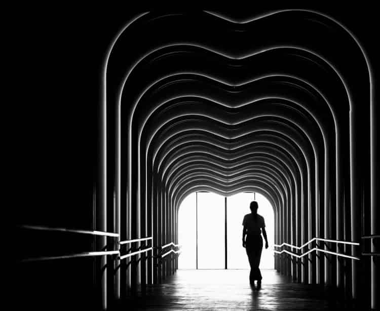 the passage - figure crossing light through stone archway in palma old town