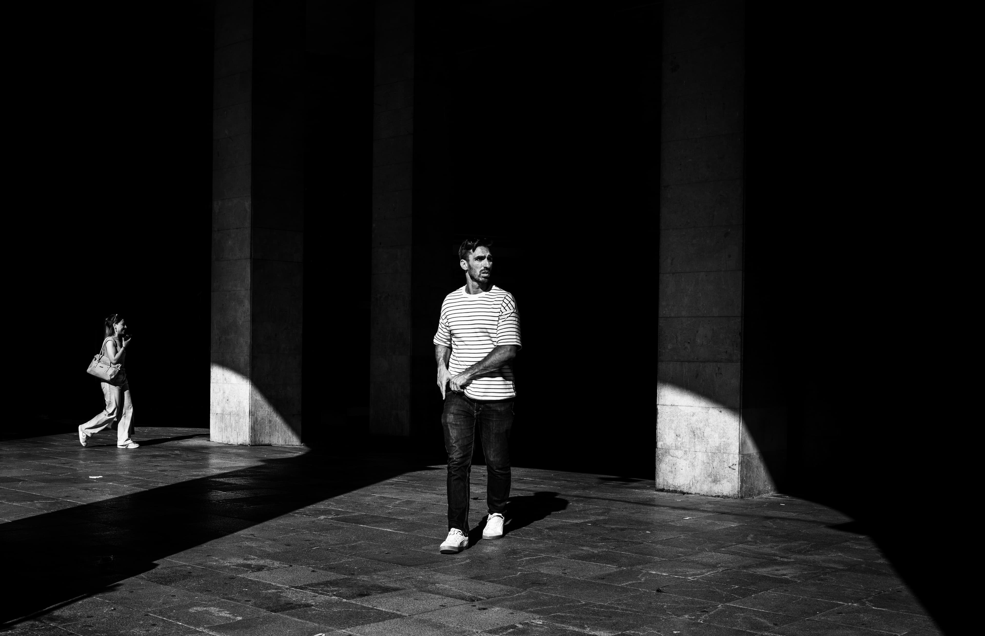 Man in striped shirt between cathedral columns, light and shadow