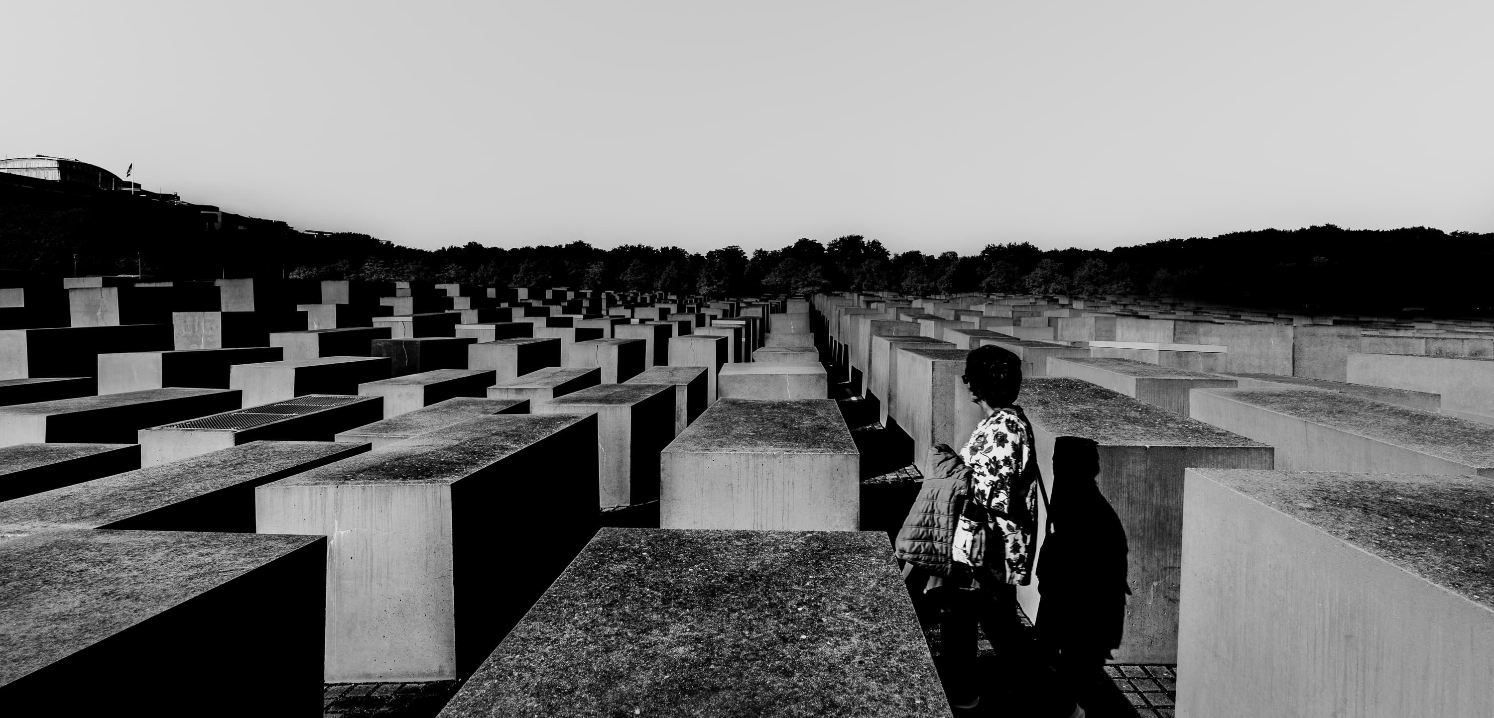 Panoramic view of the Holocaust Memorial stelae field with two visitors, Berlin — black and white documentary photography