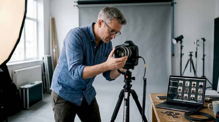 Un fotógrafo prepara su cámara antes de una sesión de retratos en su estudio.